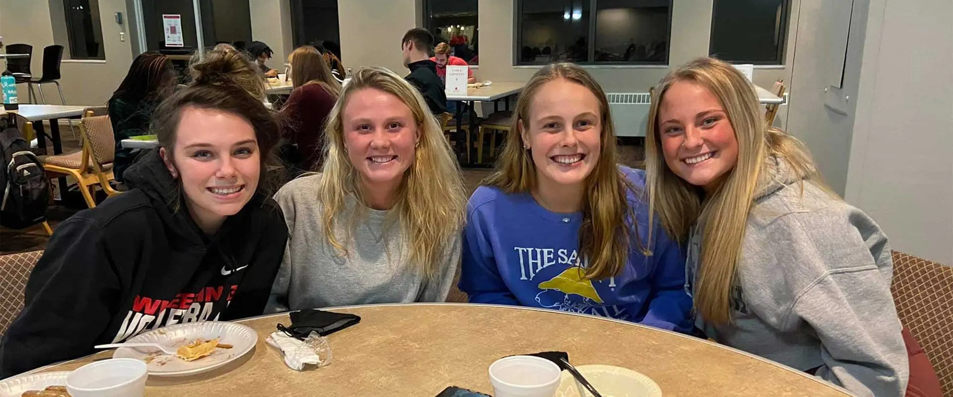 Four students sitting around table after meal in dining hall